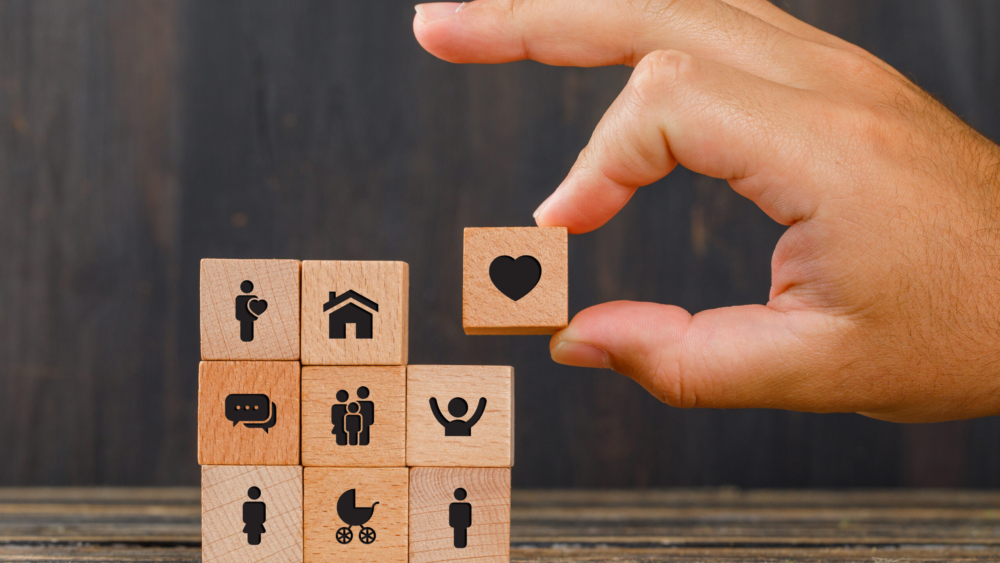 Relationship concept on wooden background side view. hand holding wooden cube with heart icon.