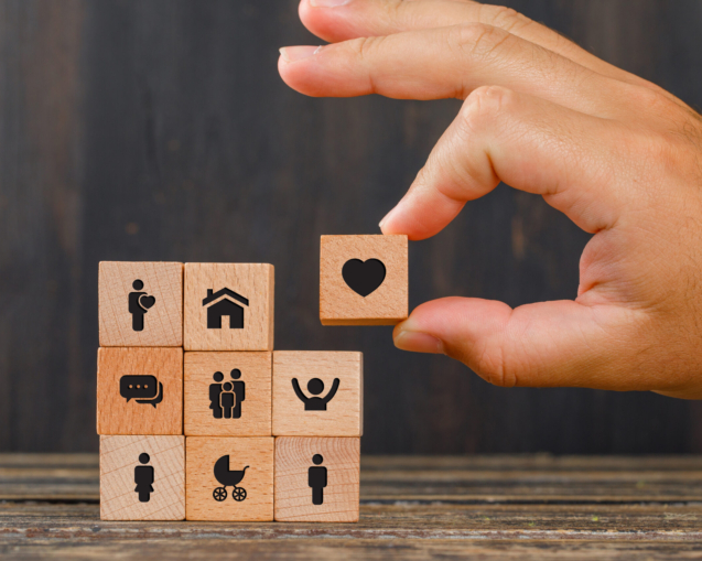 Relationship concept on wooden background side view. hand holding wooden cube with heart icon.